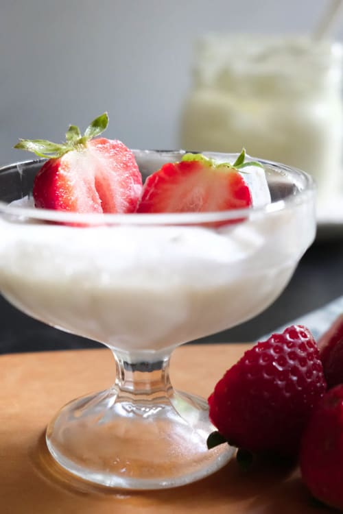 homemade crème frâiche topped with slices of strawberries in a glass