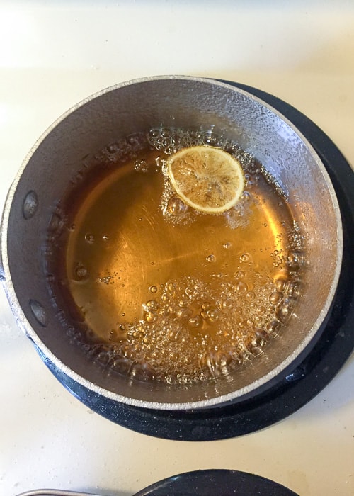 a pot of water with white sugar and slice of lemon