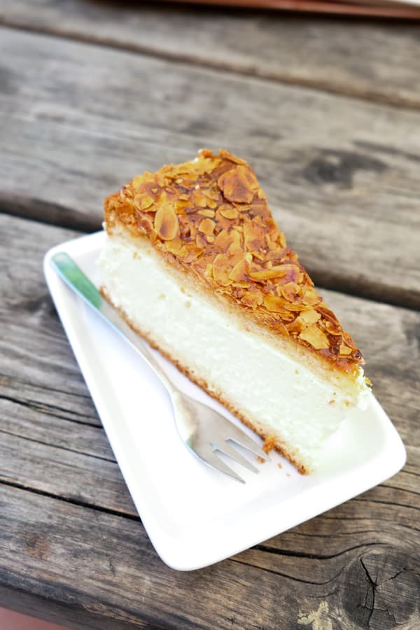 A slice of Bienenstich or Bee Sting Cake made of two layers of cake, vanilla cream filling, and caramelized almond topping