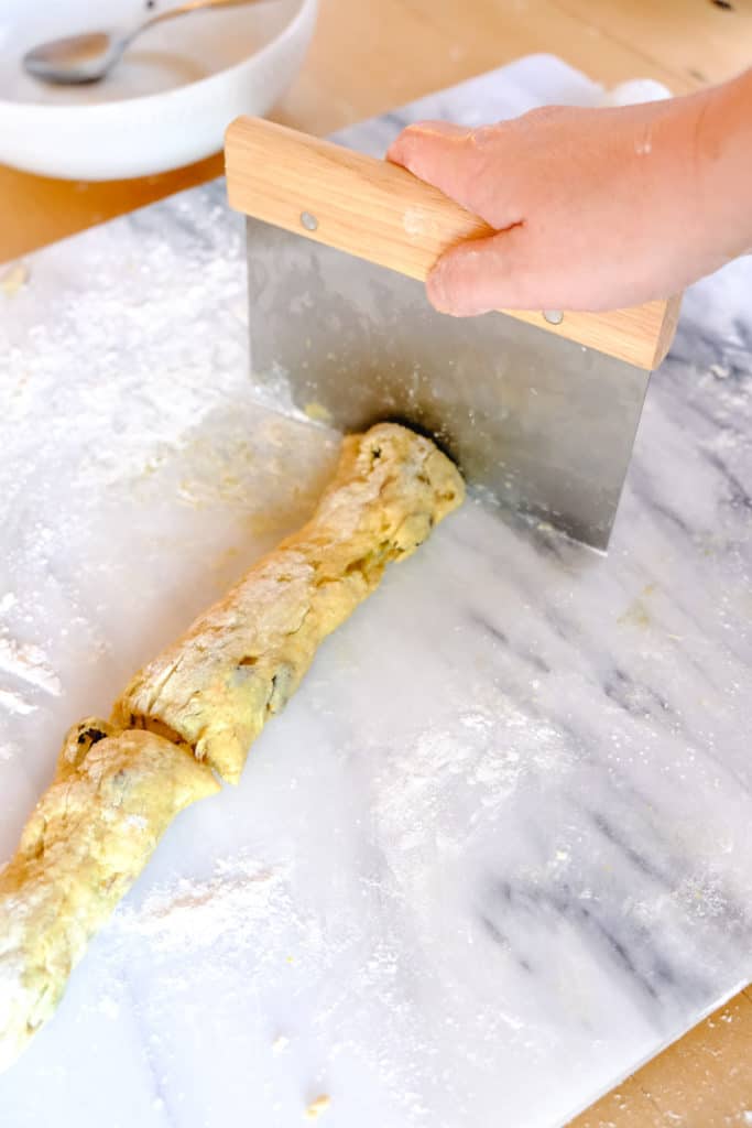 dividing a log of dough into bites using a pastry scraper