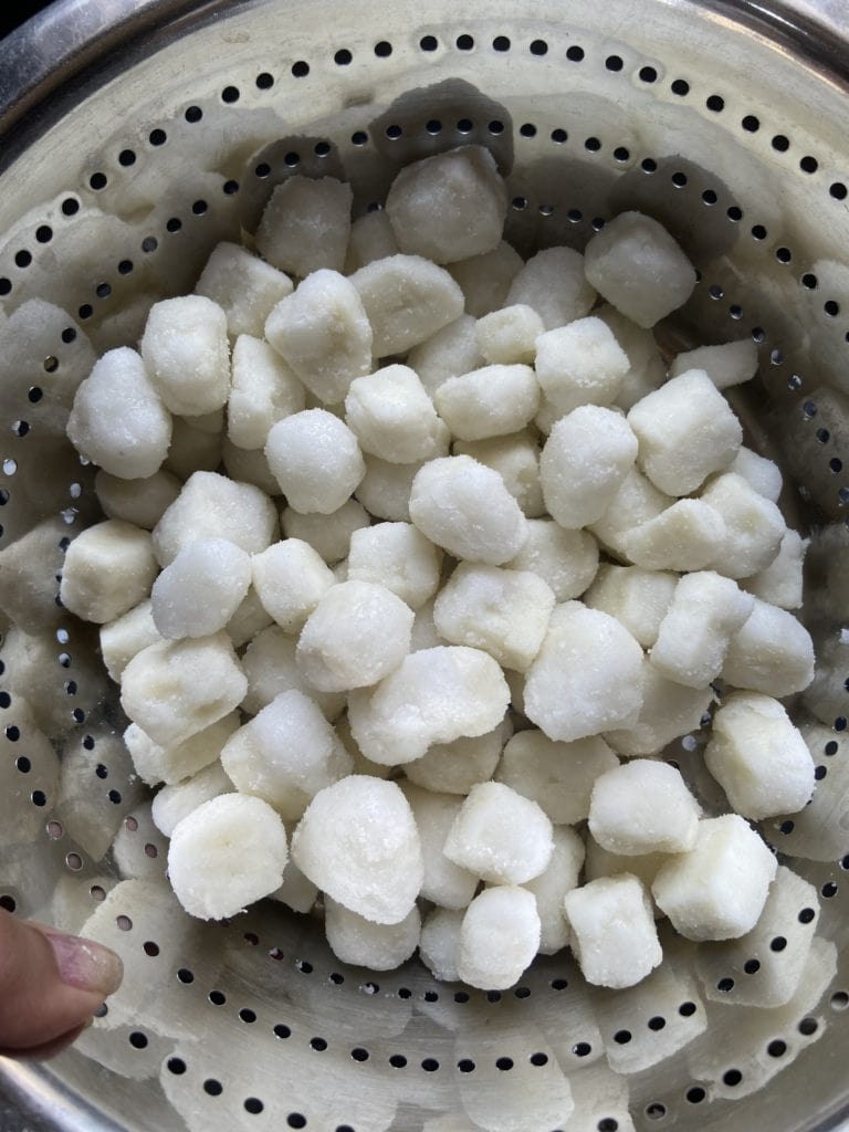 Sifting out extra sugar from paneer using a strainer with big holes.