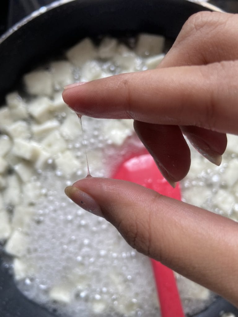 Testing the syrup between thumb and forefinger to form a single long string.