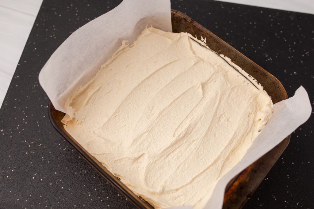 Custard mixture spread over the bottom layer of Nanaimo Bars