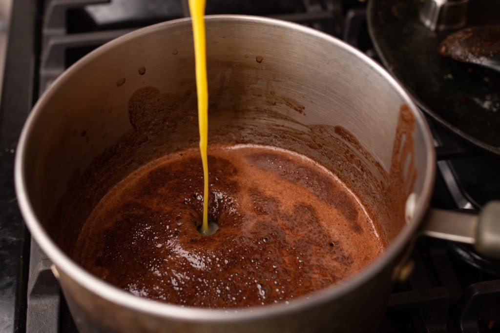 Adding beaten egg to melted butter, cocoa powder and sugar